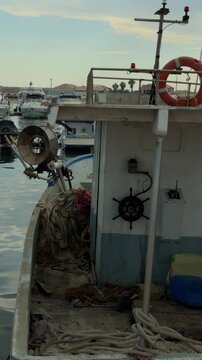 Vertical close-up aboard a traditional fishing boat in Marzamemi featuring ropes, fishing nets and the helm, highlighting Sicilian maritime craftsmanship.