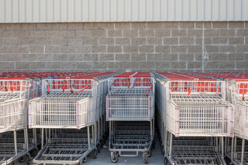 Rows of empty shopping carts lined up against a brick wall © Maxwell