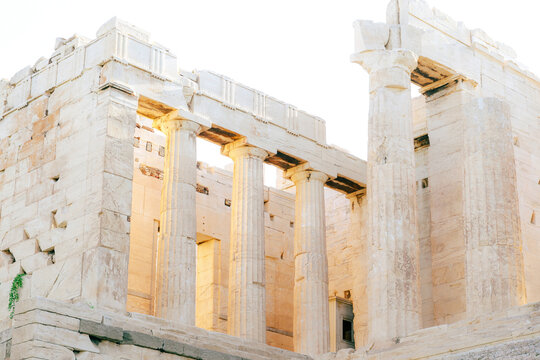 Sunlit marble columns of an ancient Greek temple at the Acropolis in Athens, showcasing classical architectural details and weathered stone texture.