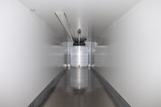 Empty clean refrigerated truck trailer interior for cold chain logistics. White industrial container for food transportation. Cargo space with cooling system inside heavy vehicle