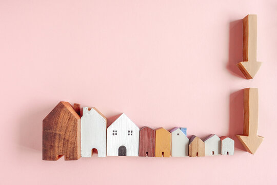 housing market, real estate crash, falling prices, property value, economic recession, financial crisis, mortgage rates shown with miniature houses and arrows on pink background.