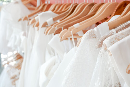wedding dress, bridal boutique, white gown, wooden hanger, lace detail, bridal shop, fashion retail display of elegant silk and lace gowns for a luxury wedding ceremony shopping experience.