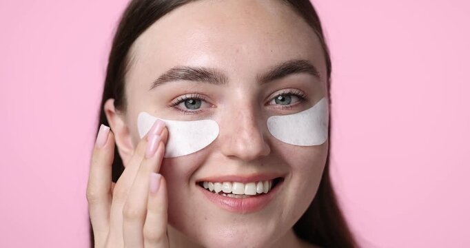 Beautiful woman with eye patches on pink background