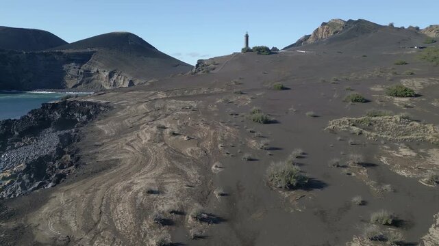 Faial Island&rsquo;s Capelinhos Lighthouse on the Azores, surrounded by volcanic terrain, rugged Atlantic coast and the landscape, aerial view