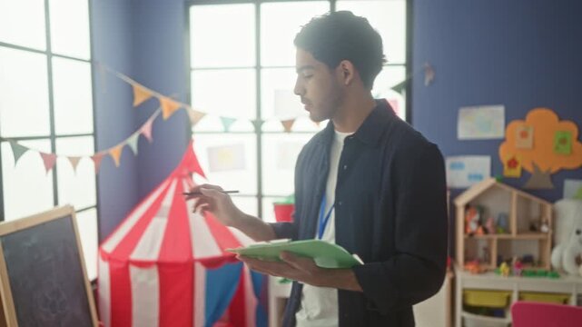 Man writing on clipboard with pen in a children's playroom building, pointing toward toys; focused care.