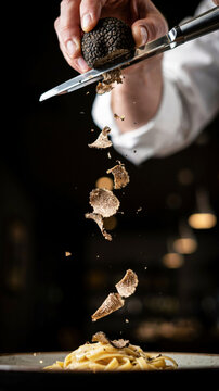 Black truffle being shaved over pasta dish in upscale dining setting