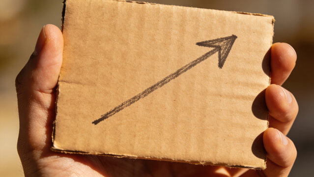 Hand holding cardboard with upward arrow, business growth concept