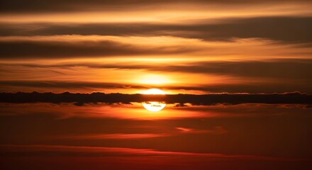 Obraz premium Sun setting behind clouds in orange sky