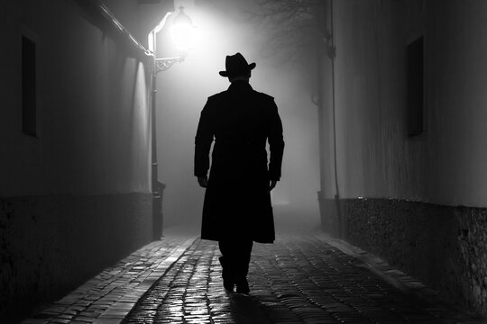 Mysterious Man Walking Through Foggy Old World Alley at Night in Noir Style in Black and White.