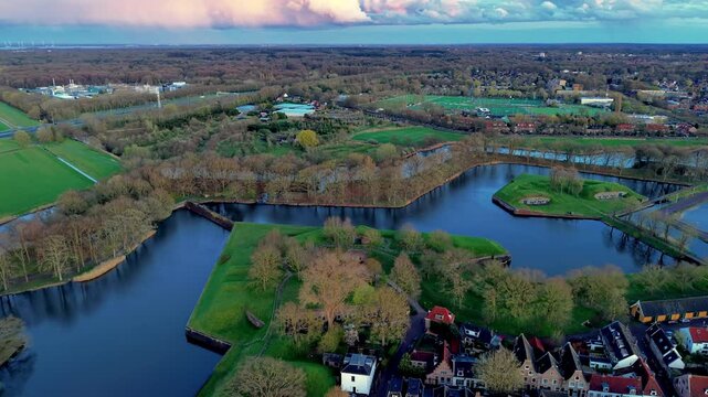 Beautiful high altitude aerial panoramic perspective of star shaped historical fort ramparts water moat channels and green parklands under a dramatic pink sunset sky during evening dusk