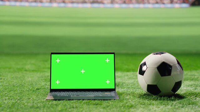 Green screen laptop mockup appears in a vertical stadium layout with blurred stands and grass, leaving editable screen space for sports promotion.