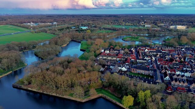 Beautiful high altitude aerial panoramic perspective of historical star shaped fortified town center red brick roofs moat canal bastions and colorful pink sunset sky during twilight dusk