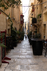 Fototapeta premium Empty outdoor bar terrace with wooden barrel tables on a narrow historic street in Valletta, Malta.