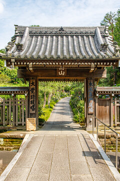 Traditional Japanese Temple Gate Opening to a Stone Pathway and Lush Garden