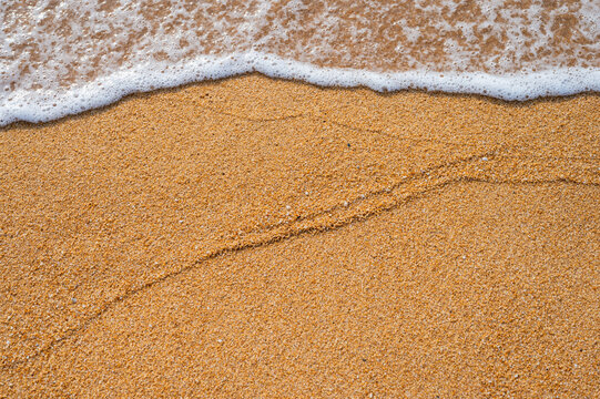 A trace left on the golden beach sand by the gentle incoming ocean tide.