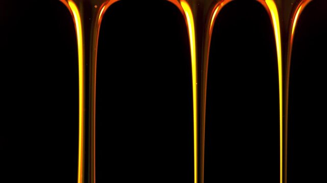 Honey dripping in thick golden streams against black background