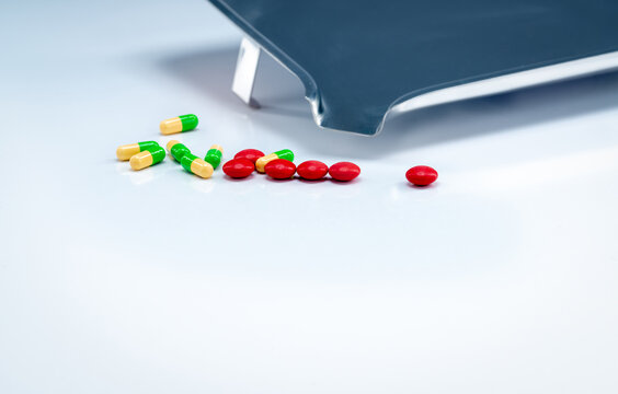 Red tablets and green-yellow capsules pills with drug tray on white table. Pharmaceutical industry. Vitamins and supplements. Pharmaceutics concept. Pharmacy products. Healthcare and medication.