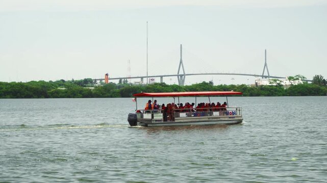 Drone aerial view of tourist boat navigating Carpintero lagoon with Tampico bridge in background on overcast day