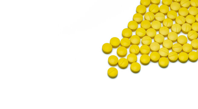Yellow small round tablets pills on white background. Healthcare concept. Painkillers medicine. Nonsteroidal anti-inflammatory drugs (NSAIDs). Pharmaceutical industry. Painkillers or analgesic drug.