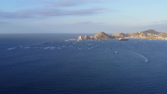 4K drone shot of a large fleet of sport fishing boats gathering near the iconic El Arco arch before the tournament start in Cabo San Lucas Bay, Los Cabos, Baja Sur, Mexico.