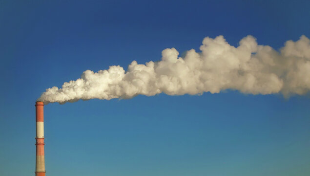 Industrial chimney releasing smoke into clouds.