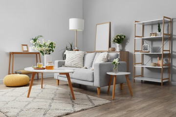 Modern living room interior with a comfortable gray sofa, white coffee table, and decorative elements © Pixel-Shot