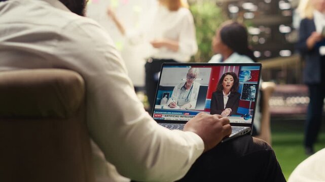 Black man watching online news segment about artificial intelligence and doctors on laptop during outdoor work break, digital media communication, informal workplace, for AI strategy.