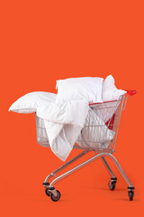 Shopping cart full of pillows on orange background © Pixel-Shot
