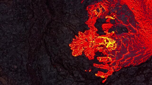 Aerial view of hot molten lava flowing down volcanic slopes creating