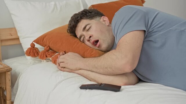 Man sleeping on bed with remote by his hand and mouth slightly open in a residential building; sleepiness.
