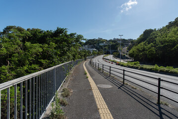 Obraz premium 快晴の空と橋の点字ブロックが続く歩道と車道