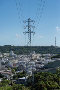 快晴の空で前後に伸びる送電線と街中の送電鉄塔