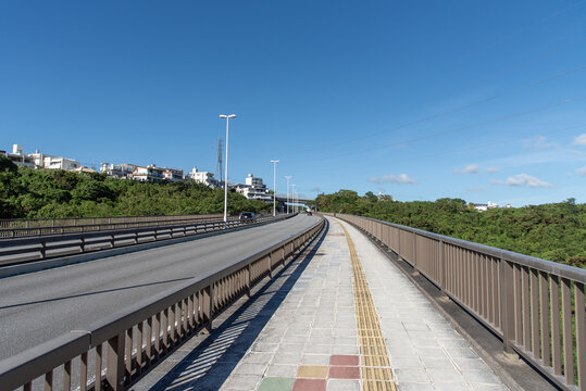 快晴の空と橋の点字ブロックが続く歩道と車道
