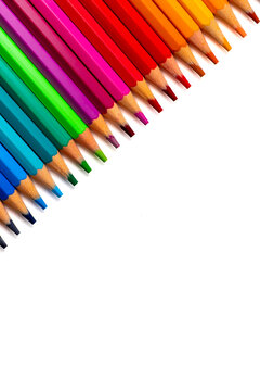 Diagonal row of colorful wooden pencils arranged in a rainbow spectrum on a white background with copy space. Art, education, creativity, design, stationery, and back to school concept.