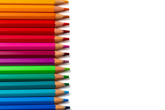 Colorful wooden pencils arranged in a rainbow spectrum on a white background with copy space. Art, education, creativity, design, stationery, and back to school concept.