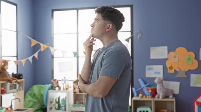 Man touching chin in a classroom building, surrounded by toys and bunting; thoughtful contemplation focus.
