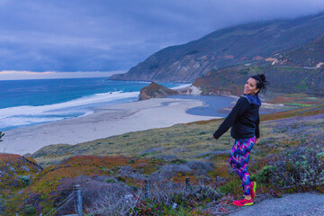 Naklejka premium Woman stands on coastal trail, smiling gently at camera