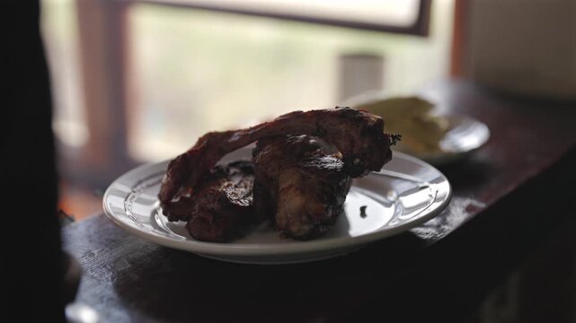 Grilled lamb chops on white plate near window.