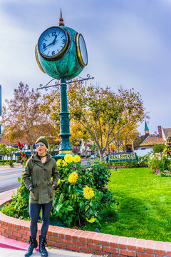 Woman smiles near whimsical green globe clock