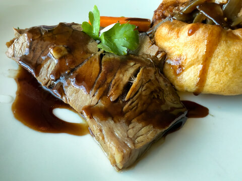 Close of view of braised beef with vegetables and stuffed bread on white dish