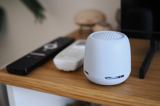 Small speaker on a wooden table with remote controls nearby