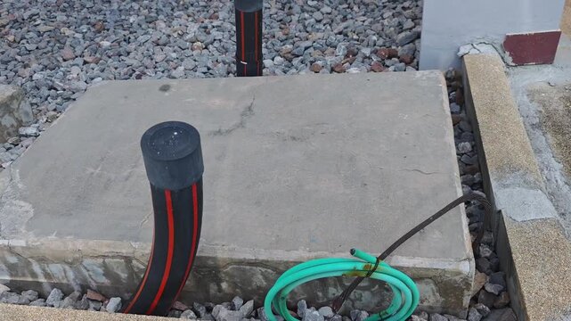 Pan right video of a concrete foundation pad for a station service transformer with underground cable pipes in a high voltage electrical substation construction site.
