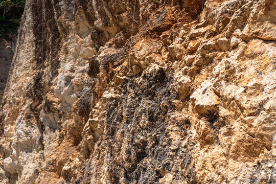 Rugged cliffs with karst and limestone layers. Dark streaks contrast with lighter rocks, hinting at erosion and time. Natural rock formations suggest depth. Ideal for nature and geology.