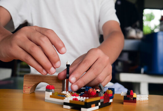 Child playing and building with colorful toy bricks, plastic blocks.	