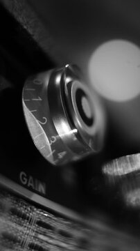 Black and White Close Up View of Hand Adjusting Gain Control Knob on Guitar Amplifier