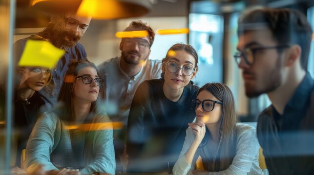 Professionals look through a transparent glass divider at sticky notes during a strategy meeting.