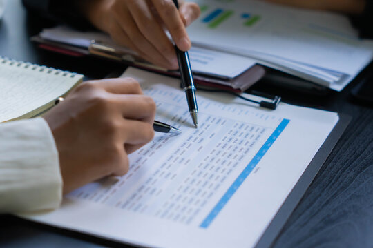 Asian businesswoman using pen pointing at document