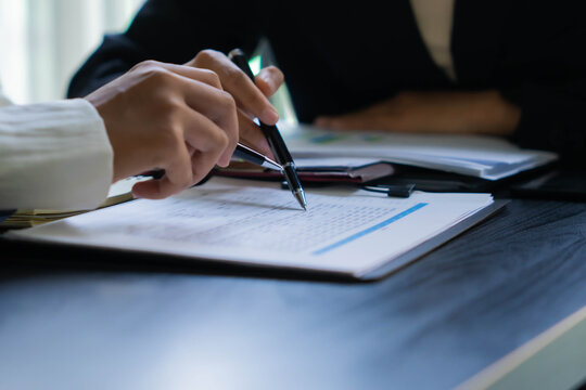 Asian businesswoman using pen pointing at document