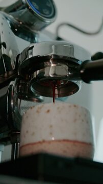 4K Pouring coffee stream from professional machine in cup. Barista man making double espresso, using filter holder. Flowing fresh ground coffee. Drinking roasted black coffee in the morning.	
