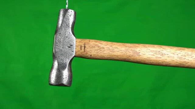 Heavy metal machinist hammer rotating slowly on a vibrant green screen background for professional vfx compositing